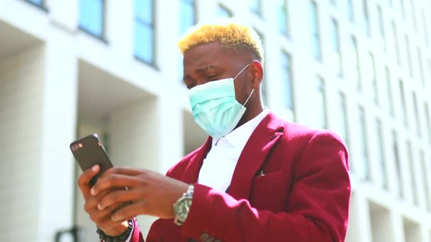 Amerykanin w kurtce Marsala pracownik czyta złe wieści na zewnątrz smartfona o drugiej fali epidemii wirusa w tle biura w centrum — Wideo stockowe