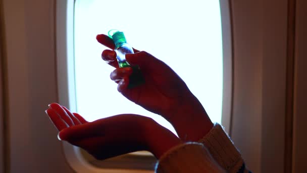 Młoda kobieta w samolocie dezynfekuje dłonie żelem, dezynfekuje podczas lotu — Wideo stockowe