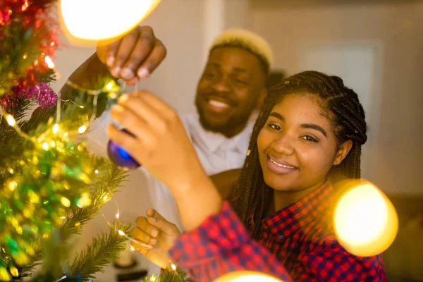 multicultural family decorating christmas tree with ball and garland