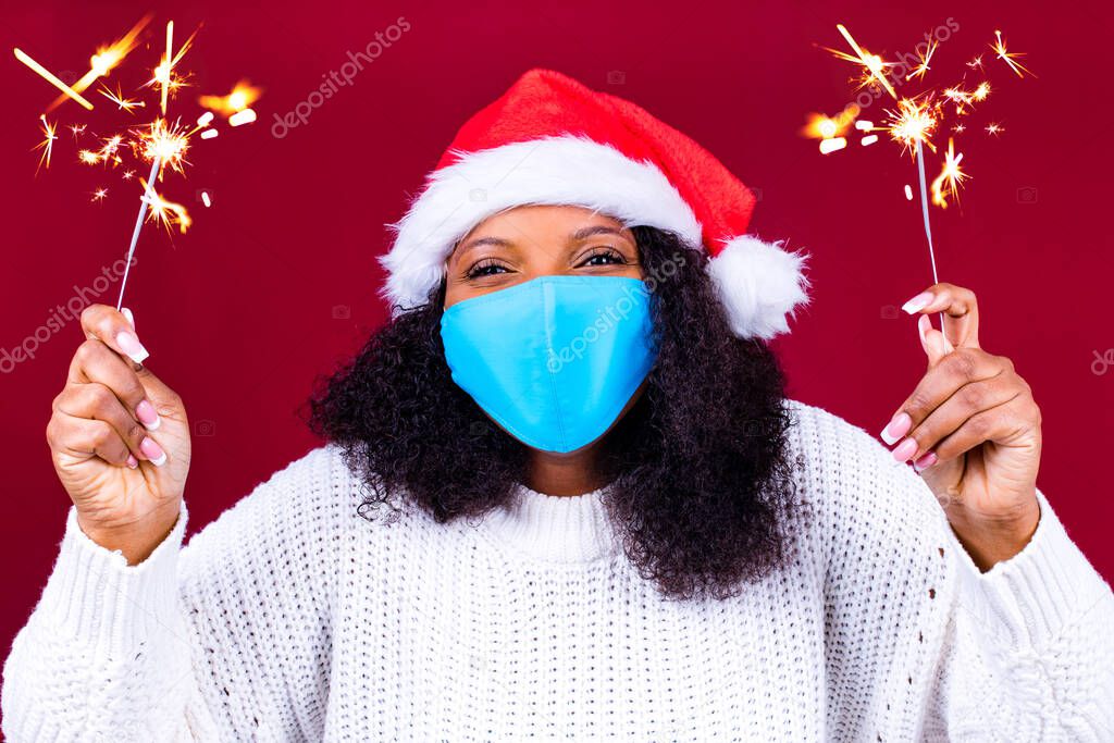 latino joyful pretty woman in medical mask and red santa claus hat laughing isolated on red background she is happy and excited full of fun