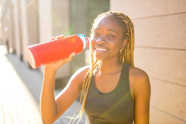 Αφροαμερικανή γυναίκα που πίνει smoothies αφού έκανε τζόκινγκ στους δρόμους του κέντρου — Φωτογραφία Αρχείου