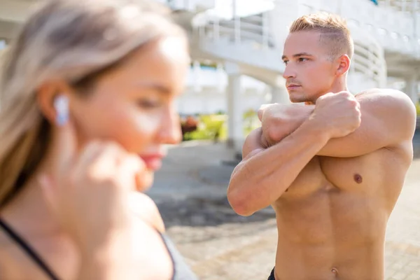 Pareja joven en traje deportivo haciendo ejercicio matutino al aire libre en verano caluroso —  Fotos de Stock