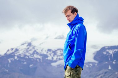 Dağlarda yağmurlu mavi ceketli adam