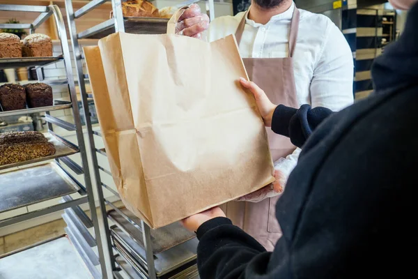 Veselý pekař doručuje chléb klientovi v obchodě — Stock fotografie