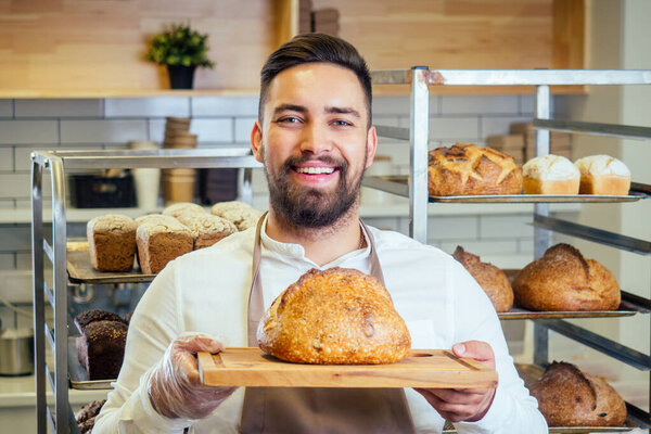 Handsome baker in uniform at the manufacturing small business owner concept