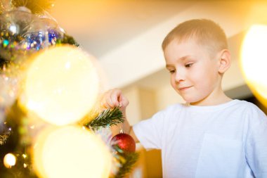 Koronavirüs nedeniyle karantinada Noel ağacını süsleyen çocuk.