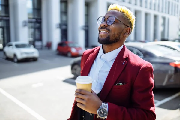 Afro-americano homem em marsala jaqueta bebe café para ir frop papel eco copo ao ar livre no centro do escritório — Fotografia de Stock