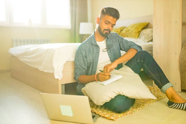 Indischer bärtiger Mann sitzt auf dem Boden und macht finanzielle Berechnungen Online-Geschäft in neuer Wohnung — Stockfoto