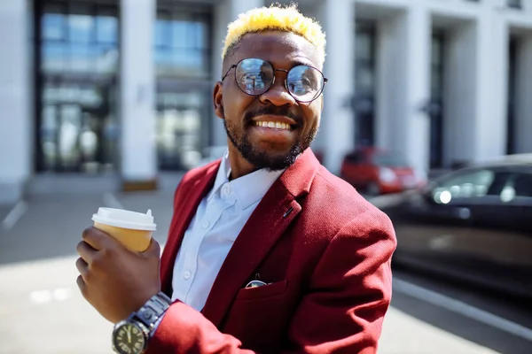 Afro-americano homem em marsala jaqueta bebe café para ir frop papel eco copo ao ar livre no centro do escritório — Fotografia de Stock