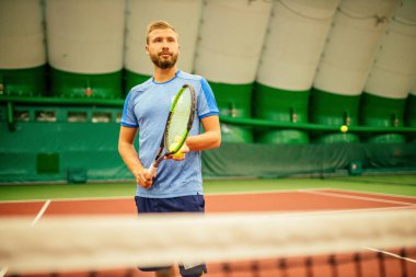 Eğitmen ya da koç içeride tenis oynamayı öğretiyor.