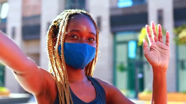 Uma afro mulher de fato de treino e uma máscara médica tira uma selfie na rua. — Vídeo de Stock