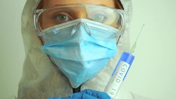 화학적 보호 마스크를 쓰고 있는 생물 학자 여성, 실험실에서 백신을 보유하고 있는 안경과 장갑 — 비디오