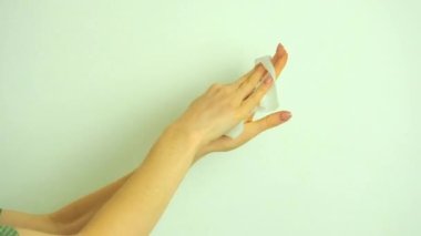 Üniversitedeki stüdyoda beyaz bir arka plana el dezenfektanı süren bir kadın.