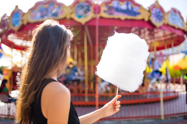 Žena jíst cukrovou vatu v létě rozmazané fotografie Rollercoaster proti modré obloze — Stock fotografie