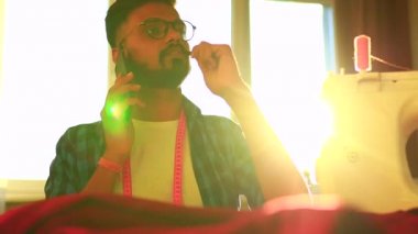 Ofisinde çalışan Hintli hippi tasarımcı telefonla konuşuyor ya da sesli mesaj kaydediyor.