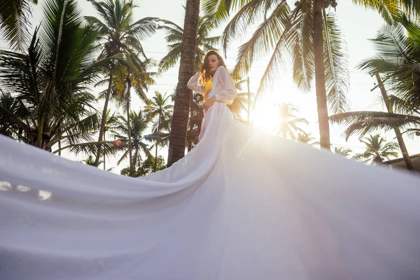 Mulher morena bonita em vestido branco com trem longo em uma praia desfrutando de solidão e liberdade — Fotografia de Stock