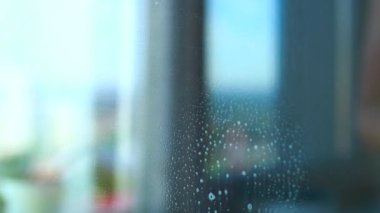 Kadın, cam pencereye antibakteriyel köpük şeklinde özel bir sıvı püskürtüyor.