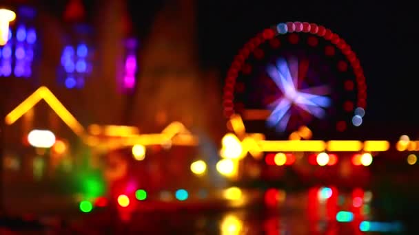Blurred unfocused video of brightly lit ferris wheel ride spinning at night — Stock Video