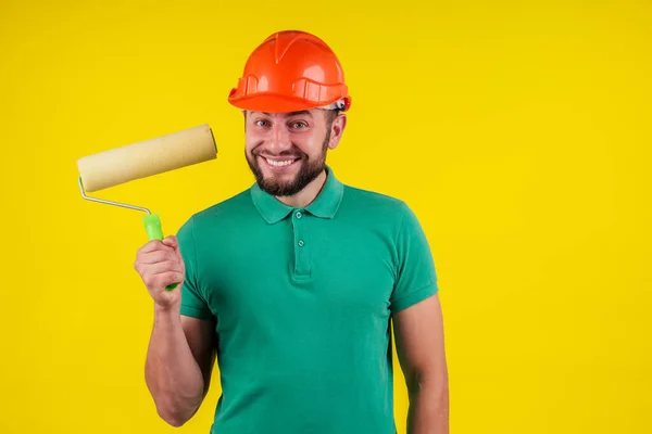 Maschio indossare un casco hardhat dipingere un muro con vernice gialla — Foto Stock