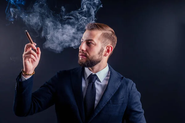 Porträtt av en attraktiv affärsman med en cigarr i svart bakgrund studio — Stockfoto