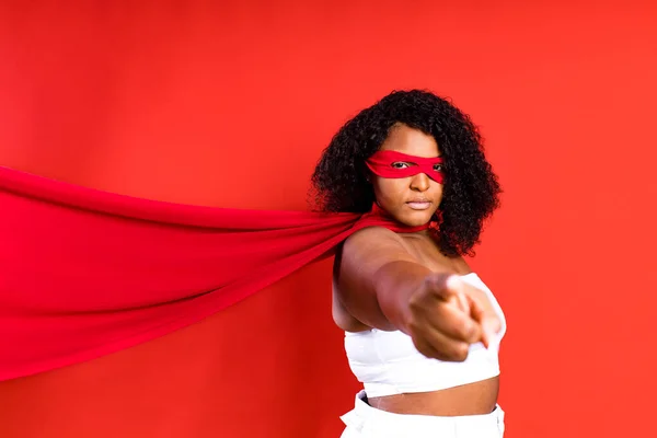 Lateinisch hispanische Frau mit roter Augenmaske und langem Superheldenmantel im Studiohintergrund — Stockfoto