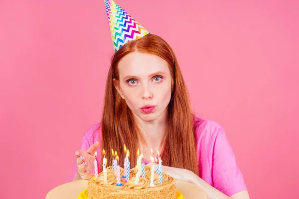 Roux roux femme faire un souhait doigts croisés, les yeux fermés souffler des bougies sur un gâteau d'anniversaire — Photo