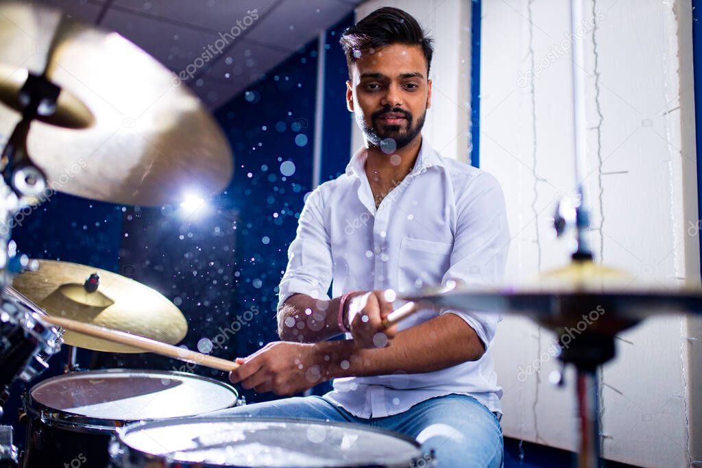 indian man playing the drums sticks close-up in recording studio