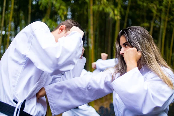 Emberek magas rúgások edzés közben taekwondo szabadban bambusz háttér — Stock Fotó