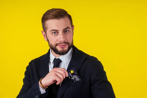 Retrato de un joven hombre de negocios guapo con tarjeta de crédito sobre fondo amarillo — Foto de Stock