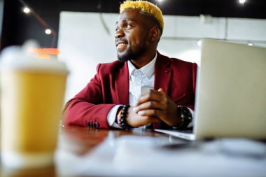 Afrikalı Amerikalı bir adam internetten eğitim alıyor ve kahve içiyor.