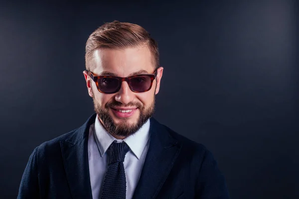 Retrato de joven hombre de negocios guapo usando gafas de sol sobre fondo negro — Foto de Stock