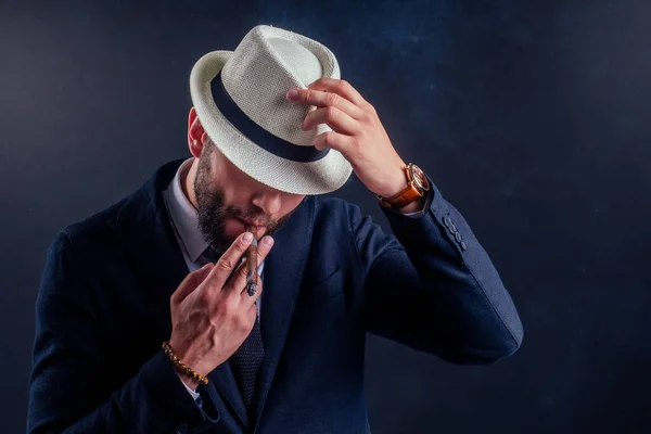 Retrato de un atractivo hombre de negocios con un cigarro en un estudio de fondo negro — Foto de Stock