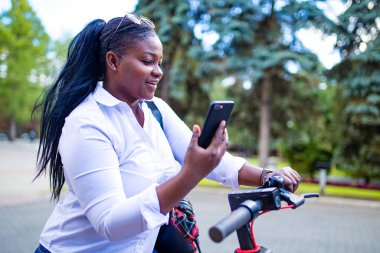 Afro-Amerikalı bir kadın kiralık bir e-scooter ya da sokakta bir e-bisiklet kiraladı ve peşin ödeme yaptı.
