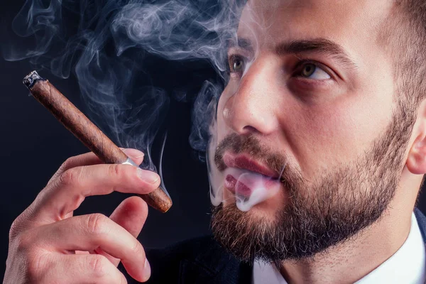 Portrait of an attractive business man with a cigar in black background studio — Stock Photo, Image