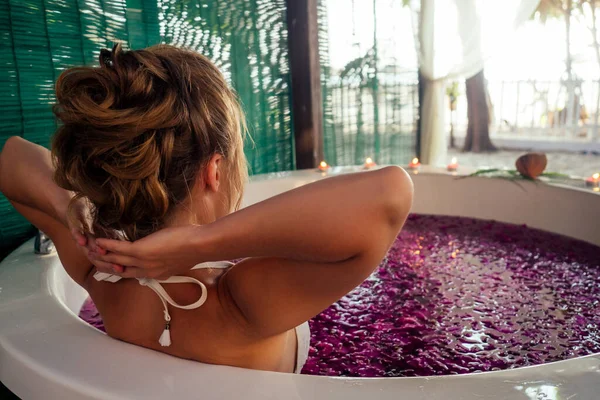 Frau entspannt sich im Bad mit tropischen Blumen im Freien eines Luxushotels — Stockfoto