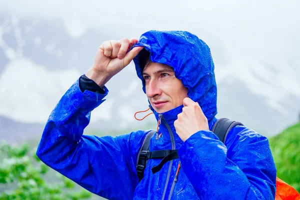 Uomo in giacca blu con pioggia in montagna — Foto Stock