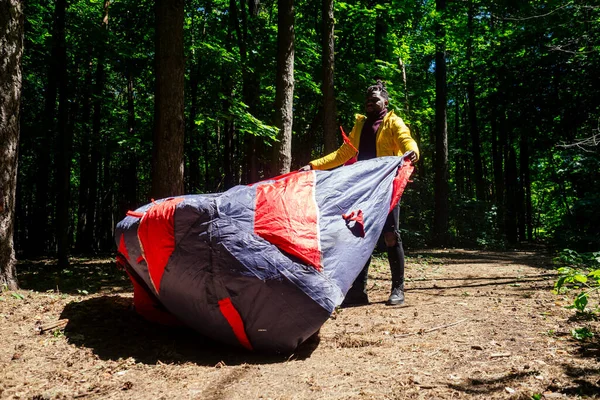 Afro-americano em amarelo jacker colocando em uma barraca na floresta — Fotografia de Stock