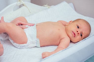 Beyaz anne ıslak mendil kullanıyor, bebek pudrası sürüyor. Dört aylık bebeğini evde yatağa yatırmadan önce.