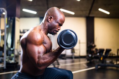 Koç, yeni spor salonunda karanlık arka planda ağırlık kaldırıyor.