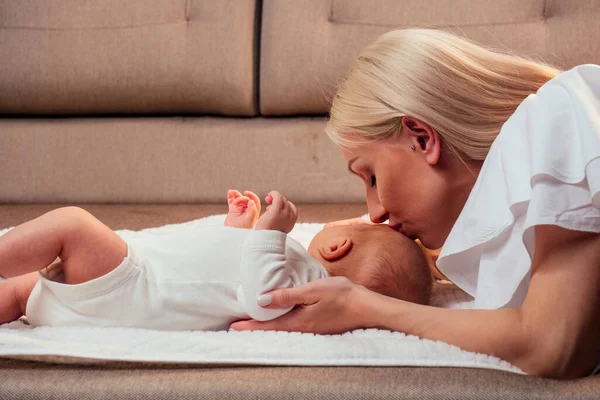 Blonde mother breastfeeding and hugging baby at cozy apartment — Stock Photo, Image