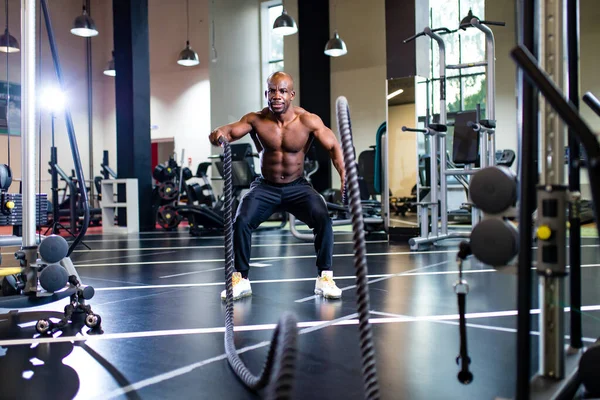 Pelatih mengangkat beban di atas latar belakang gelap di gym baru — Stok Foto