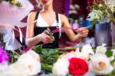 Çiçekçinin çiçek buketi yaparken çekilmiş görüntüsü.
