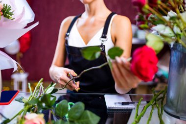 Çiçekçinin çiçek buketi yaparken çekilmiş görüntüsü.