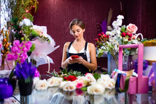 Floristin steht mit Handy-Lieferung an der Theke ihres Blumenladens — Stockfoto