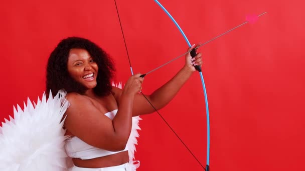 African latin cupid woman in wtite top bra holding bow and arrow in red studio The 14th of February Valentines Day — Stock Video