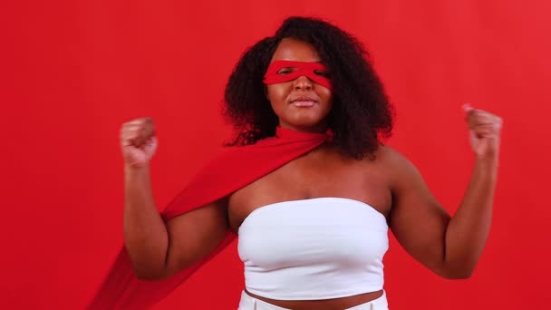 Latin hispanik wanita dalam masker mata merah dan jubah superhero panjang di latar belakang studio — Stok Video
