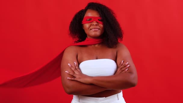 Latin hispanik wanita dalam masker mata merah dan jubah superhero panjang di latar belakang studio — Stok Video