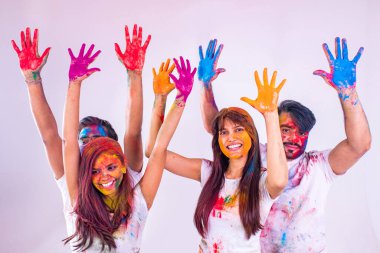 Dört mutlu arkadaş, beyaz arka plandaki stüdyoda geleneksel Holi zamanı geçiriyorlar.
