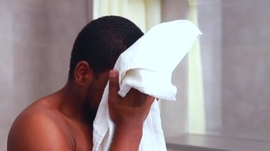 Afro-Amerikan erkek evde pamuk peçeteyle yüzünü siliyor.
