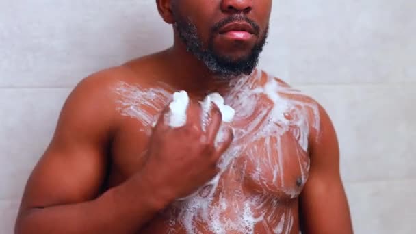 Brazylijski człowiek mycie ciała z prysznicem gąbka w białej łazience — Wideo stockowe